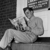 <p>Publicity photograph taken during the Second World War of a soldier sitting on the step of Fort Slocum&#39;s library, then located in Building 69, reading a movie fan magazine.</p>